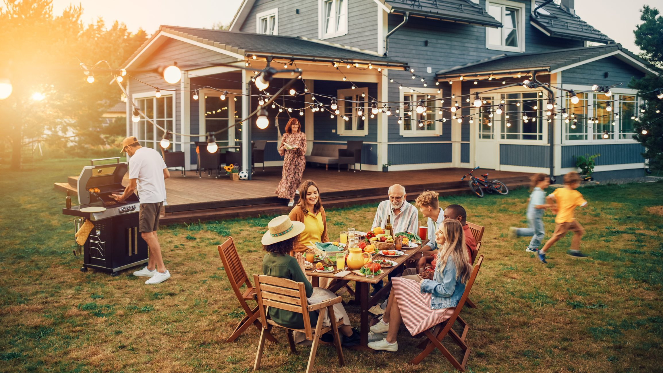Family enjoying food outside home on dinner table and children playing
