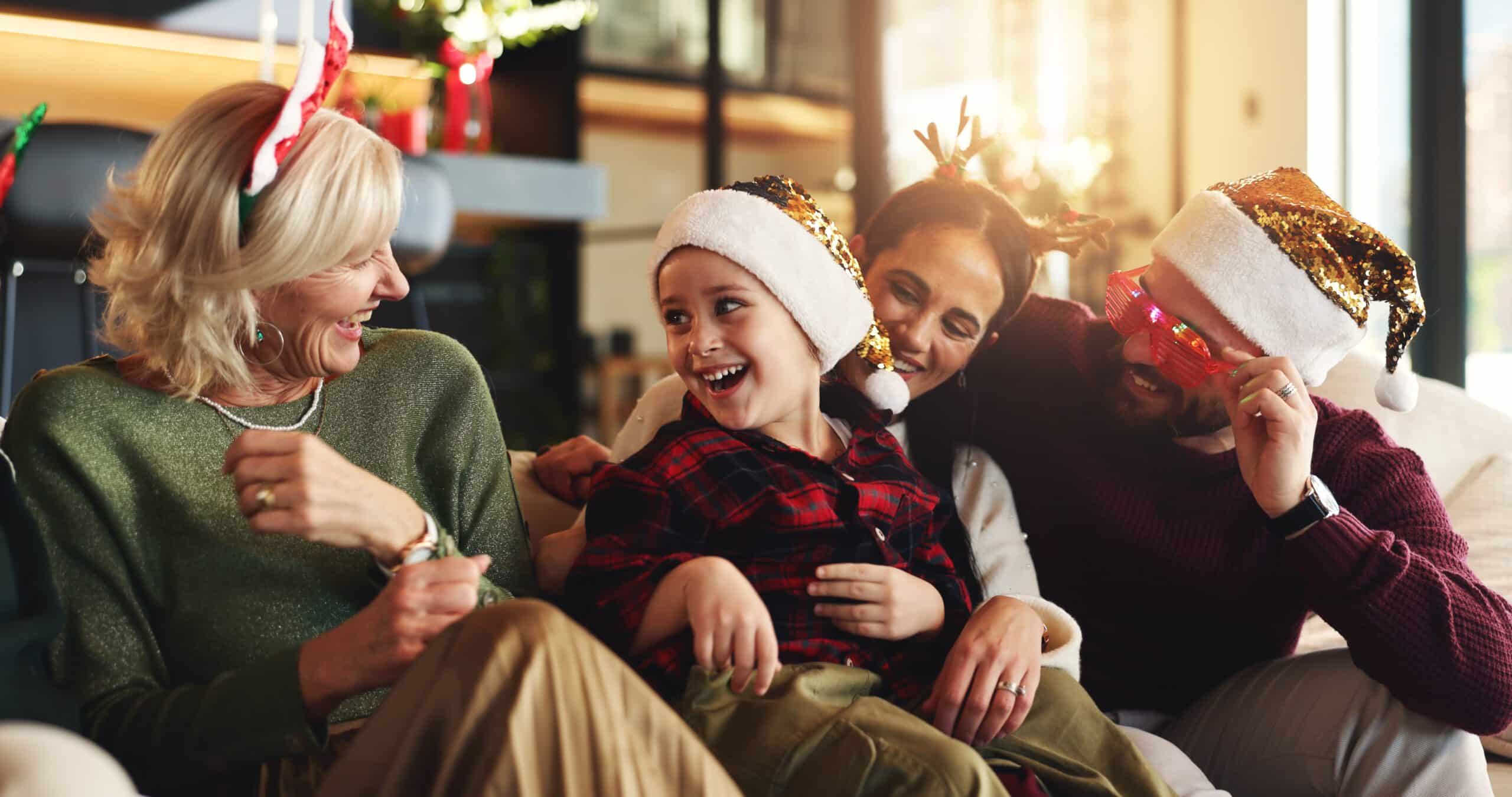 Family, generations and child on sofa for Christmas, festive season and bonding on holiday. Happy, home and girl with mom, dad and grandparents laugh on sofa for tradition, celebration and xmas